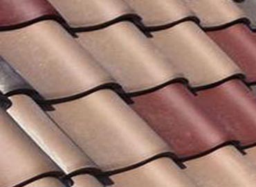 Construction worker uses a power drill to attach a cap the the top of a sheet metal roofing job with screws.